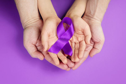 Hands holding purple ribbon to support and spread awareness for Crohn's Disease.